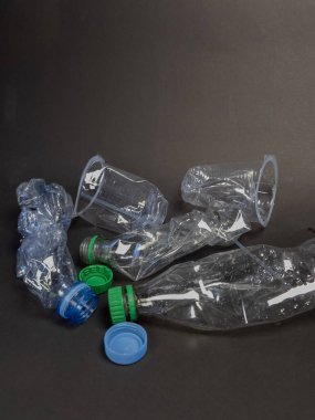 Bu resim, karanlık bir yüzeye saçılmış parçalanmış plastik şişe ve bardaklardan oluşan bir koleksiyon sergiliyor. Fotoğraf, plastik atık ve çevresel kaygıları vurguluyor. Kompozisyon basit, dokulara odaklanarak. 