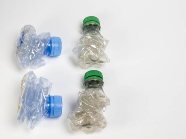 Bazıları çoktan ezilmiş ve geri dönüştürülmeye hazır plastik şişeler. Beyaz arkaplanda izole