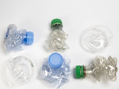 Bazıları çoktan ezilmiş ve geri dönüştürülmeye hazır plastik şişeler. Beyaz arkaplanda izole