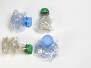 Bazıları çoktan ezilmiş ve geri dönüştürülmeye hazır plastik şişeler. Beyaz arkaplanda izole