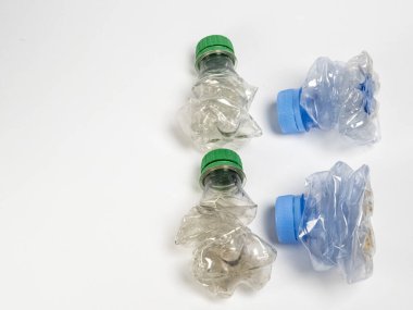 Bazıları çoktan ezilmiş ve geri dönüştürülmeye hazır plastik şişeler. Beyaz arkaplanda izole
