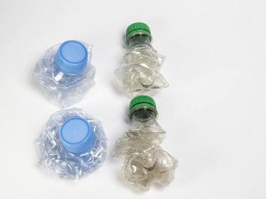 Bazıları çoktan ezilmiş ve geri dönüştürülmeye hazır plastik şişeler. Beyaz arkaplanda izole