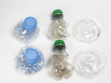 Bazıları çoktan ezilmiş ve geri dönüştürülmeye hazır plastik şişeler. Beyaz arkaplanda izole