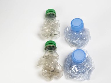 Bazıları çoktan ezilmiş ve geri dönüştürülmeye hazır plastik şişeler. Beyaz arkaplanda izole