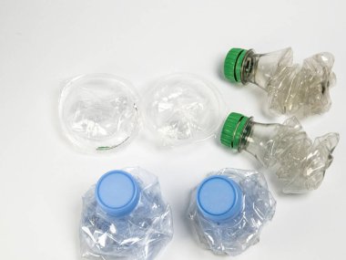Bazıları çoktan ezilmiş ve geri dönüştürülmeye hazır plastik şişeler. Beyaz arkaplanda izole
