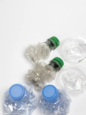 Bazıları çoktan ezilmiş ve geri dönüştürülmeye hazır plastik şişeler. Beyaz arkaplanda izole