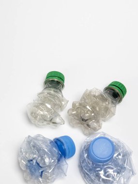 Bazıları çoktan ezilmiş ve geri dönüştürülmeye hazır plastik şişeler. Beyaz arkaplanda izole