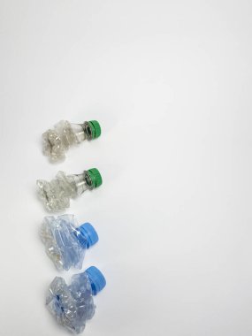 Bazıları çoktan ezilmiş ve geri dönüştürülmeye hazır plastik şişeler. Beyaz arkaplanda izole