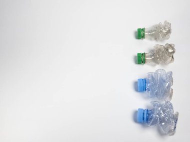 Bazıları çoktan ezilmiş ve geri dönüştürülmeye hazır plastik şişeler. Beyaz arkaplanda izole