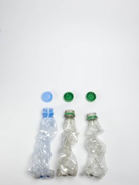 Bazıları çoktan ezilmiş ve geri dönüştürülmeye hazır plastik şişeler. Beyaz arkaplanda izole