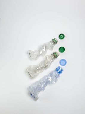 Bazıları çoktan ezilmiş ve geri dönüştürülmeye hazır plastik şişeler. Beyaz arkaplanda izole
