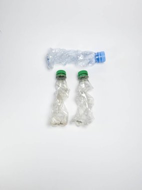 Bazıları çoktan ezilmiş ve geri dönüştürülmeye hazır plastik şişeler. Beyaz arkaplanda izole