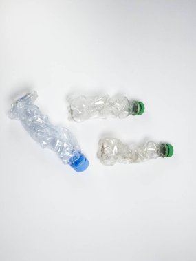 Bazıları çoktan ezilmiş ve geri dönüştürülmeye hazır plastik şişeler. Beyaz arkaplanda izole