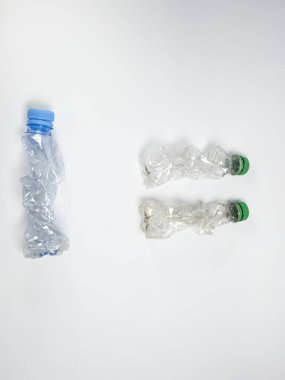 Bazıları çoktan ezilmiş ve geri dönüştürülmeye hazır plastik şişeler. Beyaz arkaplanda izole