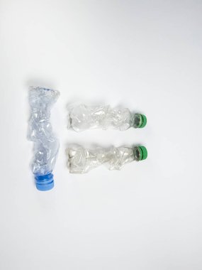 Bazıları çoktan ezilmiş ve geri dönüştürülmeye hazır plastik şişeler. Beyaz arkaplanda izole
