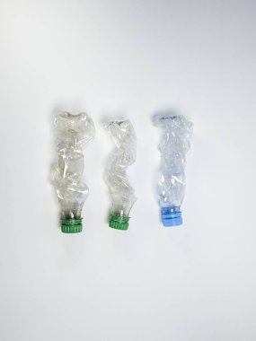 Bazıları çoktan ezilmiş ve geri dönüştürülmeye hazır plastik şişeler. Beyaz arkaplanda izole