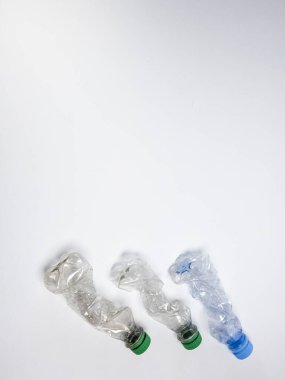 Bazıları çoktan ezilmiş ve geri dönüştürülmeye hazır plastik şişeler. Beyaz arkaplanda izole