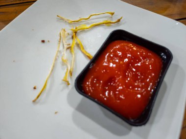 Yemekten sonra arta kalan kızarmış yemek ve ketçapla beyaz bir tabakta