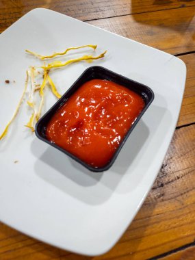 Yemekten sonra arta kalan kızarmış yemek ve ketçapla beyaz bir tabakta