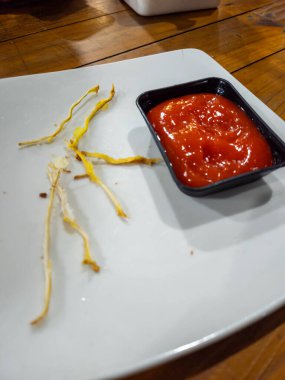 Yemekten sonra arta kalan kızarmış yemek ve ketçapla beyaz bir tabakta