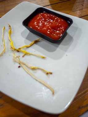 Yemekten sonra arta kalan kızarmış yemek ve ketçapla beyaz bir tabakta