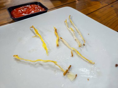 Yemekten sonra arta kalan kızarmış yemek ve ketçapla beyaz bir tabakta