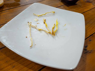 Tahta bir masada yemek yedikten sonra beyaz tabakta kalan yemek.