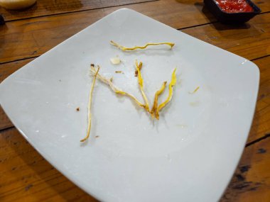 Tahta bir masada yemek yedikten sonra beyaz tabakta kalan yemek.