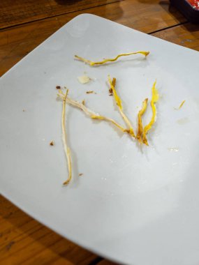 Tahta bir masada yemek yedikten sonra beyaz tabakta kalan yemek.