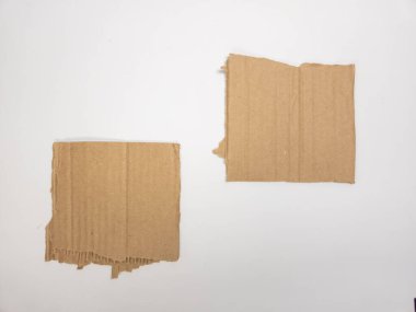 Beyaz arka planda izole edilmiş iki kahverengi karton parçası. Karton yırtılmış, bu da iç kısmı ortaya çıkarıyor. Parçalar ayrı olarak düzenlenir ve çeşitli tasarım uygulamaları için basit ama etkili bir kompozisyon sunulur. Görüntü...