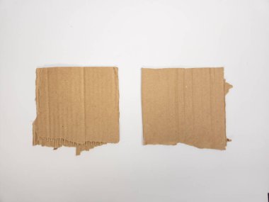Her biri kare şeklinde iki parça yırtık karton, beyaz bir zemin üzerine serilmiştir. Kartonda görünen kıvrımlar, pürüzler, yırtık kenarlar var. Bu da kesilmiş ya da yırtılmış olduğunu gösteriyor. Işıklandırma eşit, ve kompozisyon basit, odaklanmak 