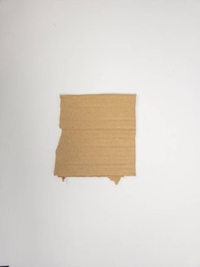 Yırtık kahverengi bir karton parçasının, beyaz bir arka planda izole edilmiş yakın plan, tepeden çekilmiş bir fotoğrafı. Mukavvanın pürüzlü, dokulu bir yüzeyi ve görünür kıvrımları var. Kenarları pürüzlü ve yırtık. Kullanılmış ya da yeniden tasarlanmış bir madde olduğunu gösteriyor. Th