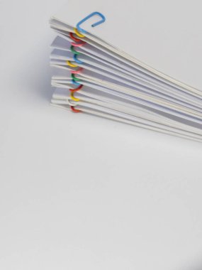 Mavi, kırmızı, sarı, yeşil ve pembe renkli ataçlarla tutturulmuş beyaz kağıtların yakın plan çekimi. Kağıtlar fan benzeri bir şekilde düzenlenmiştir. Organizasyon ya da belge koleksiyonu önerilir. Arka plan sade.