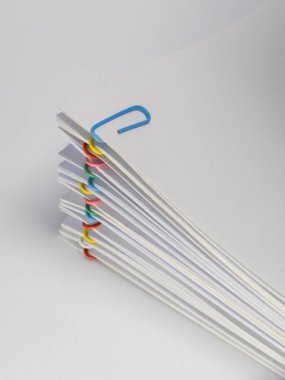 Renkli ataçlarla tutturulmuş beyaz kağıtların yakın plan çekimi. Evraklar yayılmış, düzen ve düzen duygusu yaratıyor. Görüntü iyi ışıklandırılmış, temiz beyaz bir arkaplanı var. Bu fotoğraf conc göstermek için mükemmel