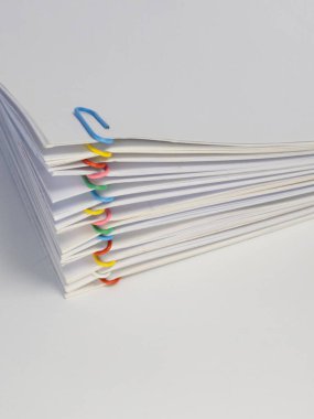 Çeşitli renkli ataçlarla tutturulmuş beyaz kağıt yığınının yakın plan görüntüsü. Kağıtlar düzgünce istiflenmiş ve parlak ataçlar temiz beyaz arka plana renk katıyor. Resmetmek için mükemmel kavramlar.