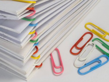 Yakın plan çekimlerde çeşitli renkli ataçlarla korunan beyaz kağıt yığınları sergilenir. Beyaz yüzeye birkaç farklı renk klipsi serpiştirilerek görsel olarak çekici bir kontrast oluşturulmuştur. Bu görüntü hastalık için mükemmel.