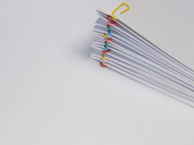 Renkli ataçlarla tutturulmuş beyaz kağıt çarşafların yakın plan çekimi. Kağıtlar çapraz olarak düzenlenir, düzen ve düzen duygusu yaratır. Beyaz arkaplan, p 'yi vurgulayarak temiz ve dağınık bir arkaplan sağlar