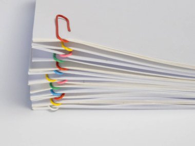 Renkli ataçlarla tutturulmuş beyaz kağıtların yakın plan çekimi. Kağıtlar yayılmış ve ataçlar farklı renklerde. Arka plan bembeyaz, temiz ve minimalist bir estetik oluşturuyor. Görüntü iyi aydınlatılmış ve...