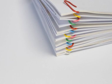 Çeşitli renkli ataçlarla tutturulmuş beyaz kağıtların yakın plan çekimi. Evraklar düzgünce düzenlenir, düzen ve düzen duygusu yaratır. Resim, beyaz kağıt ve renkli ataçlar arasındaki karşıtlığı vurgular