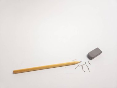 Tahta bir kalem ve gri bir silgiyle çekilen minimalist bir stüdyo resmi. Silgi kalem talaşlarının yanına yerleştirilmiş. Silme ya da düzeltme eylemi olduğunu gösteriyor. Nesneler beyaz arkaplanda, karşıtlığı ve basitliği vurguluyorlar.