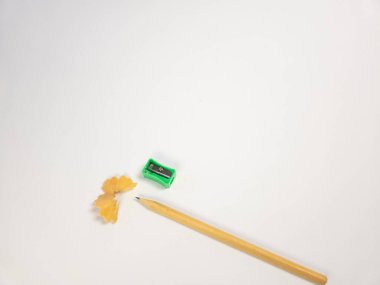 Bu resim, keskinleştirilmiş bir kalem, yeşil bir kalem açacağı ve temiz beyaz bir arkaplanda sıralanmış ahşap talaşlarını gösteriyor. Kompozisyon basit ve minimalistik, yazma ve çizim için kullanılan araçları vurguluyor. Odaklandığımız nokta t 'nin hassasiyeti.