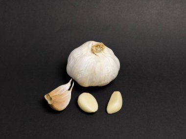 Yakın çekim bir stüdyo çekiminde üç ayrı karanfil ile birlikte koyu ve sade bir arkaplanı olan bir sarımsak ampulü bulunur. Işıklandırma, sarımsağın dokusunu ve şeklini belirtiyor. Kompozisyon basit, ham maddeleri vurguluyor.,