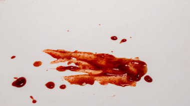 Kırmızı sıvının temiz ve beyaz bir yüzeye sıçraması ve damlamasının soyut görüntüsü. Görüntü, daha küçük damlaların etrafa saçıldığı merkezi bir lekeyi gösteriyor ve görsel olarak ilginç bir model oluşturuyor. Kırmızı renk beyaz arkaplan ile çelişiyor, vurgula