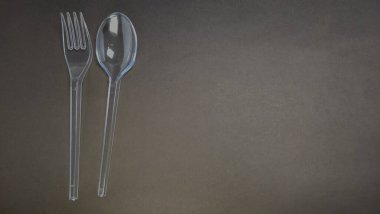 Yakın çekim bir stüdyo çekiminde koyu gri bir yüzeye karşı yan yana dizilmiş şeffaf bir plastik çatal ve kaşık yer alır. Mutfak aletleri sol tarafta, sağda geniş negatif alan bırakıyorlar. Işıklandırma şeffaflığı vurguluyor.