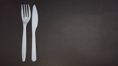 Tepeden çekilen bir karede siyah arkaplana dayanan beyaz plastik bir çatal ve bıçak bulunur. Çatallar dikey pozisyonda, çatal sol tarafta ve bıçak da sağ tarafta. Bu resim basit ve çeşitli amaçlar için kullanılabilir.