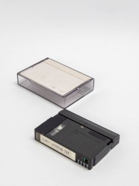 Beyaz bir yüzeyde duran antika bir kasetin yakın çekim görüntüsü. Video kasetin üzerinde 