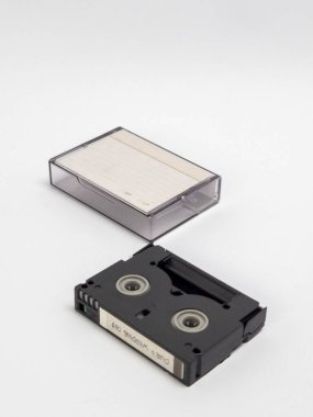 Küçük bir kasetin stüdyo çekimi ve temiz beyaz arka planda izole edilmiş temiz, koruyucu plastik kılıfı. Kasette 