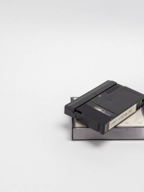 Beyaz arka planda üst üste dizilmiş iki miniDV video kaseti. En üstteki kasette 