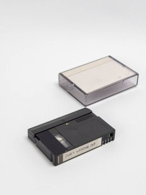 Beyaz bir yüzey üzerinde plastiği olan bir MiniDV kasetinin stüdyo çekimi. Kasette 