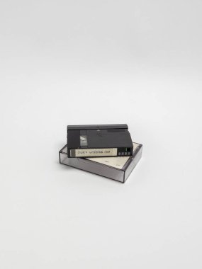 Bir natürmort fotoğrafında şeffaf plastik kutusunun üzerinde duran klasik bir düğün kaseti bulunur. Siyah bantta 